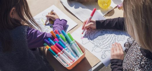 Dvě děti kreslí u stolu s fixy a pastelkami – ilustrační fotografie