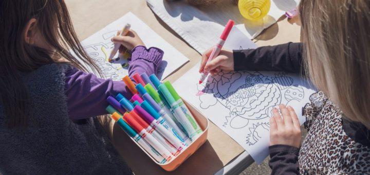 Dvě děti kreslí u stolu s fixy a pastelkami – ilustrační fotografie
